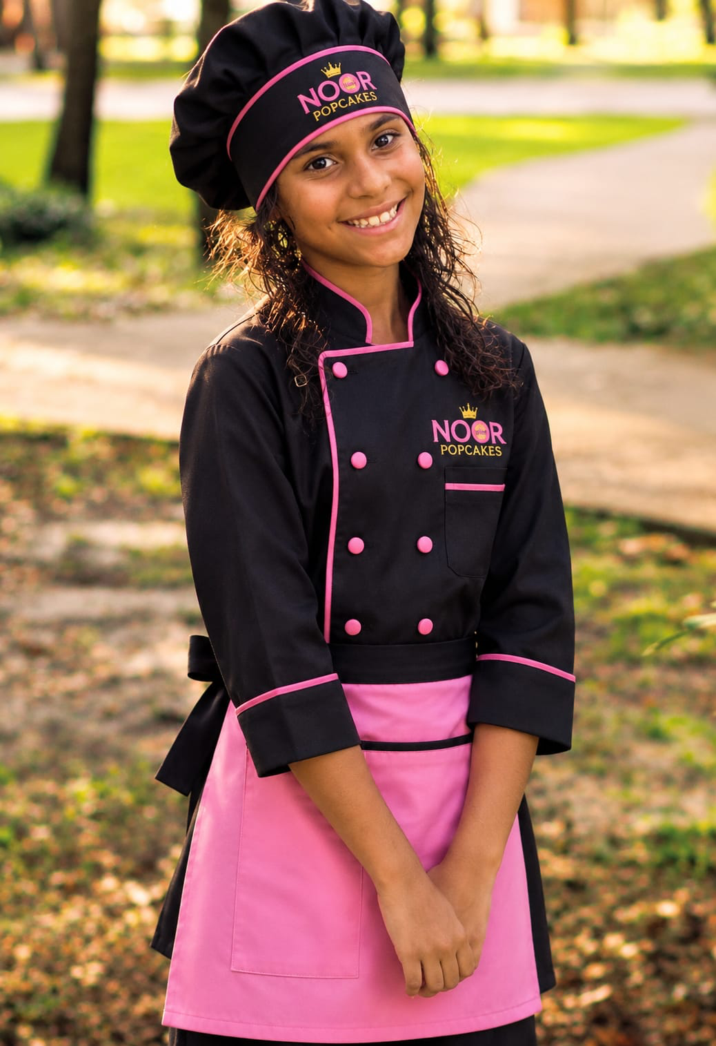 Autumn Russo, age 9, co-founder and junior chef at Noor Popcakes, wearing a hot pink chef uniform